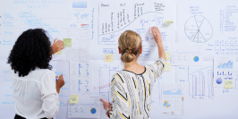 business women collaborating and writing on a whiteboard